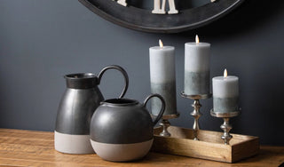 Stone-effect flameless LED candles and ceramic jugs on a wooden console – modern rustic home décor from Lucidora.