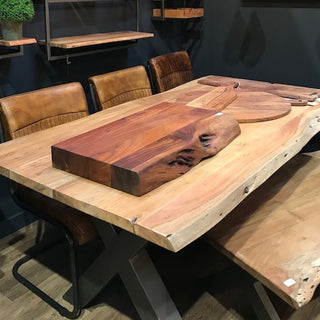 Chunky wooden chopping boards and rustic dining table with leather chairs in a modern industrial kitchen.