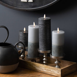 A black and white decorative pot with three lit candles placed on top, creating a warm and inviting atmosphere.