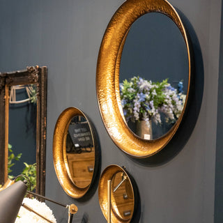 Three round mirrors arranged on a wall above a decorative vase, creating a stylish and modern interior design element.
