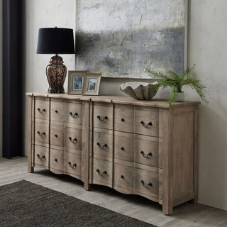 Rustic wooden dresser with black handles, topped with decor including a lamp, frames, and ceramic bowl beneath abstract art.