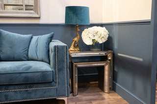 A blue couch and a standing lamp are positioned in a cozy room, creating a comfortable and inviting atmosphere.