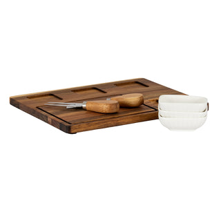 Angled view of the acacia board showing recessed serving sections and stacked bowls.