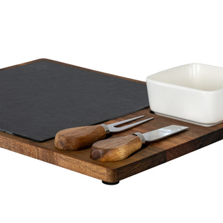 Detail of the acacia cheese board featuring the slate insert, white bowl, and two wooden-handled cheese tools.