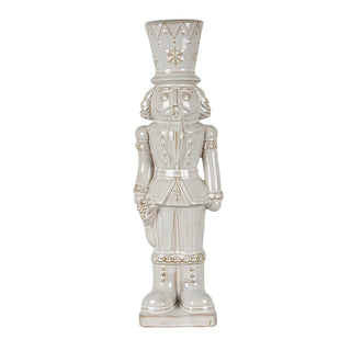 Tall ceramic nutcracker figure in light cream glaze with gold detailing on the uniform and hat.
