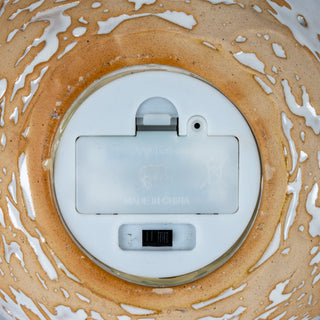 Detail of the base showing the battery compartment cover, on/off switch, and mottled ceramic glaze.