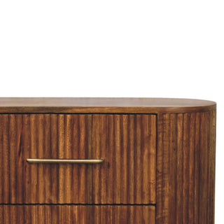 Rounded corner of the amber oak chest showing the ridged texture and smooth top surface.