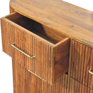Close-up of the amber oak chest showing the top drawer pulled open and the vertical ridged texture.