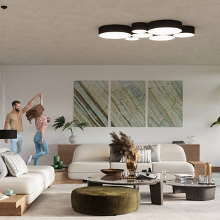 Modern living room setting featuring a large cluster of black cylindrical ceiling lights above light-coloured sofas.