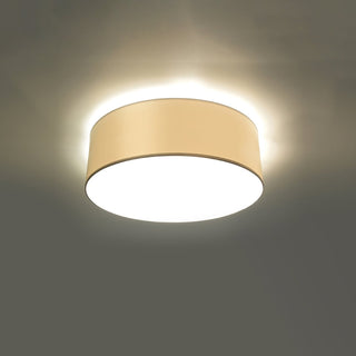 White fabric drum ceiling lamp illuminated, showing the light spill creating a halo effect on the ceiling.
