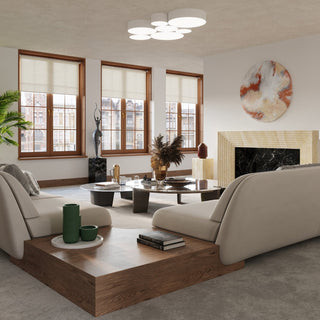Styled modern living room showing the ceiling light cluster above low seating, large windows, and a marble fireplace.