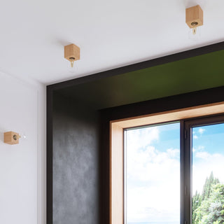 Natural wood lamps mounted on the ceiling and wall around a dark window frame, showing versatile use.