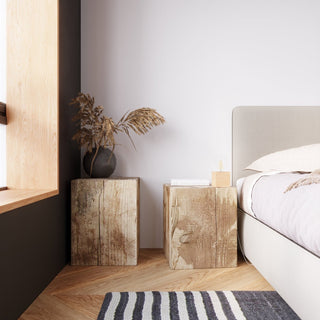 Styled bedroom scene showing the square wooden lamp base used as a table light on a rustic block.