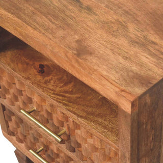 A close detail of the golden teak wood grain, carved drawer fronts, and brass bar handles.