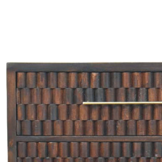 Close-up of the dark wood drawer front featuring repeated carved cylindrical texture and a brass bar handle.