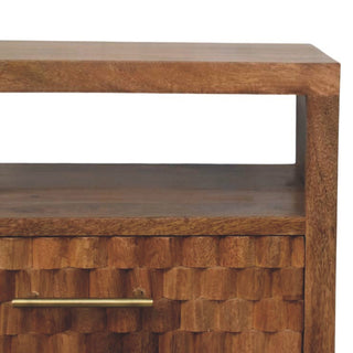 Upper right detail of the teak bedside showing the open storage shelf and the deeply carved drawer face.