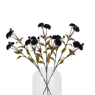Black artificial chrysanthemum stems arranged as a bouquet in a transparent vase.