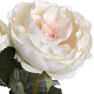 Extreme close-up of the artificial rose bloom, showing layered creamy white and pale blush fabric petals.