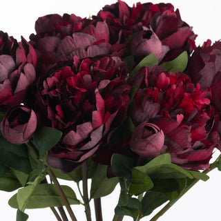 Close view of the deep burgundy petals and buds of the artificial peony rose bouquet, with green leaves visible.