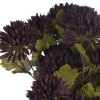 Detail shot of multiple artificial chocolate chrysanthemum blooms and textured green foliage.
