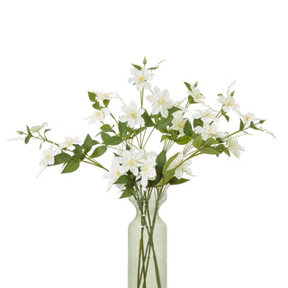 Artificial clematis spray displayed in a tall, pale green glass vase against a white background.