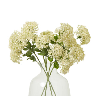 A bunch of artificial cream sedum sprays arranged in a clear glass vase on a white background.