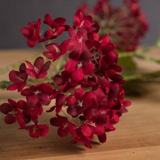 Close-up detail of the artificial crimson viburnum flower heads on a wooden surface.