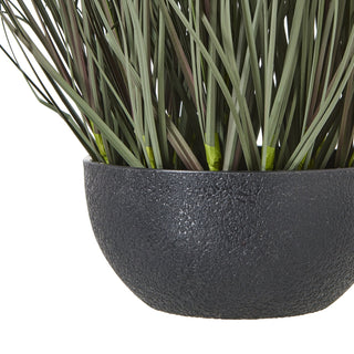 Detail shot showing the rough texture of the dark grey pot and the base of the artificial grass stems.