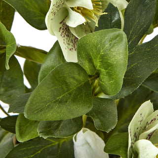 Close detail of the artificial hellebore's textured green leaves and pale spotted flowers.
