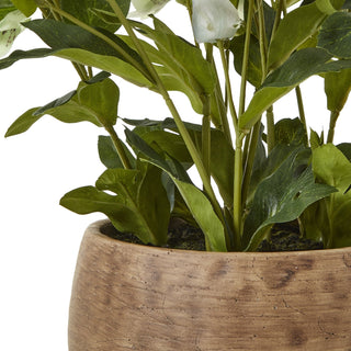 Close detail of the textured taupe planter rim, showing the base of the artificial hellebore stems and faux moss.