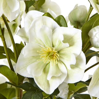 Extreme close-up of one artificial white hellebore flower showing the yellow centre and green-tinged petals.