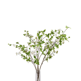 Multiple artificial mock orange sprays arranged in a clear glass vase against a white background.