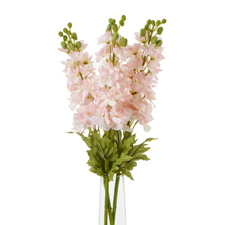 Multiple pink delphinium stems grouped in a clear glass vase, showing green leaves and lower stems.