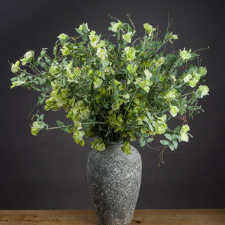 Artificial light green sweet pea stems arranged in a tall speckled grey vase.