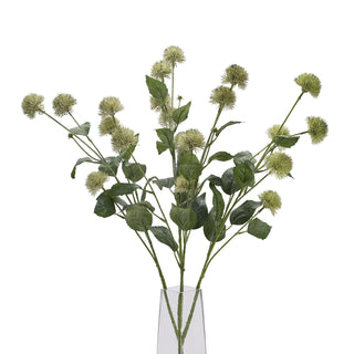 Bouquet of artificial thistle globe stems and leaves in a clear rectangular glass vase.