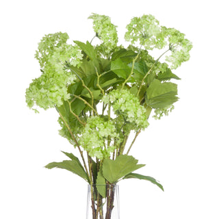 Artificial green viburnum stems and leaves displayed upright in a clear glass vase against a white background.