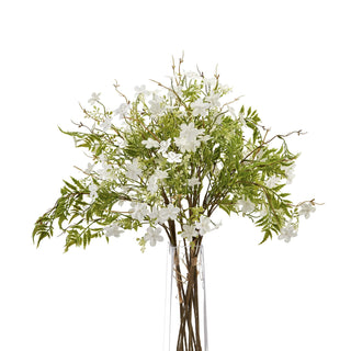 Voluminous bouquet of white bellflowers and fern-like foliage displayed in a clear cylindrical vase.