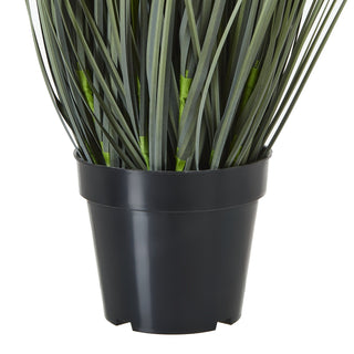 Detail shot of the artificial plant's black plastic pot and the base of the green grass foliage.