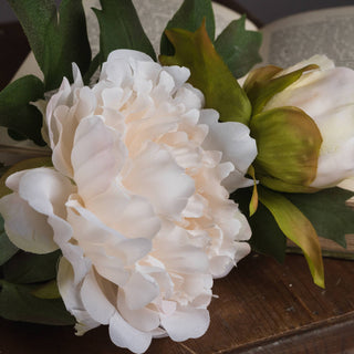 Close-up showing the layered petals of the artificial white peony bloom and a bud.