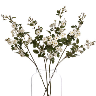 Five artificial white rose stems fanned out in a clear glass jar, studio shot against white.