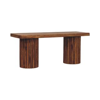 Dark wood bench with rectangular seat and two cylindrical fluted supports, shown at an angle.