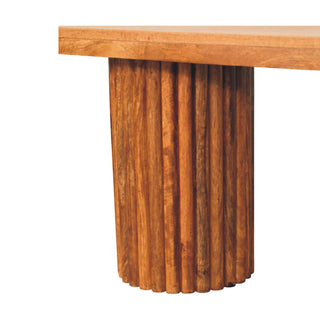 Tight close-up of the wooden bench support, showing the texture of the vertical fluting and base.