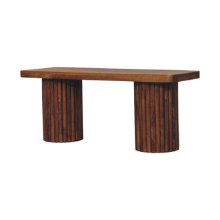 Low angle view of the dark wood bench showing the rectangular seat and fluted cylindrical supports.