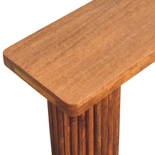 Corner detail of the wooden bench seat and the textured cylindrical fluted leg.