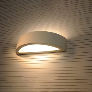 Ceramic wall light fixture illuminated, showing the up and down light wash effect on patterned wallpaper.