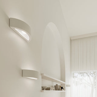 Two ceramic wall lights mounted vertically in a neutral interior with an archway and sheer curtains.