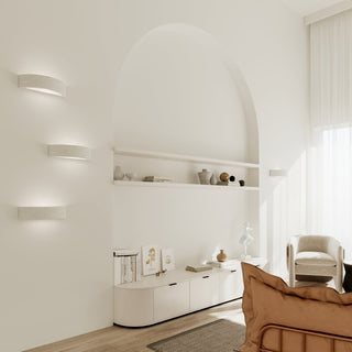 Three lights stacked vertically next to an archway recess in a neutral, light-filled room.