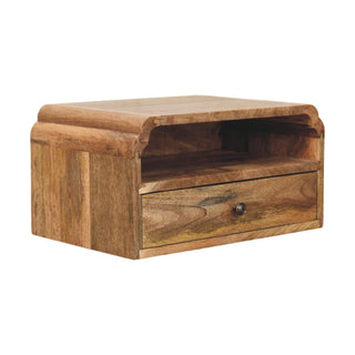 Three-quarter angle of the mango wood bedside unit, highlighting the rounded top edge and drawer with metal pull.