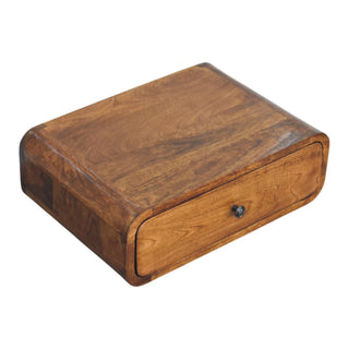 Angled view of the wall-mounted nightstand, highlighting its depth, rounded edges, and rich honey wood grain.