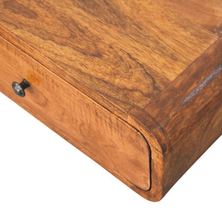 Extreme close-up showing the rich honey wood grain on the top surface and the curved front edge.
